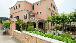 A two-story house with a stone wall in front, a garden with various plants, and a parked scooter. - Idyllic flat just 200 metres from the beach with taxi boat connection to Rovinj (Rovinj)