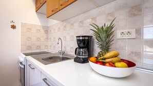 Eine Küche mit einer Edelstahl-Spüle, einer Kaffeemaschine und einer Obstschale auf der Arbeitsfläche.