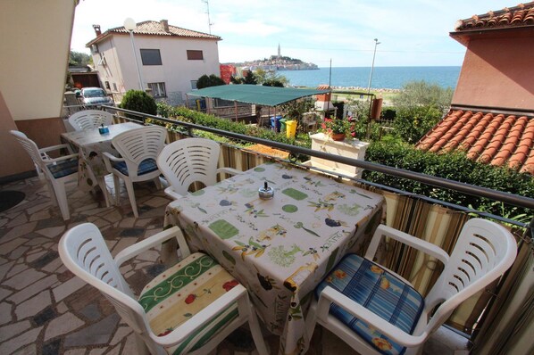 Enjoy a meal on the outdoor terrace with a view of the sea and surrounding buildings.