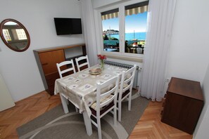 Enjoy meals for two in this cozy dining area with a table set and a view of the coastal town.