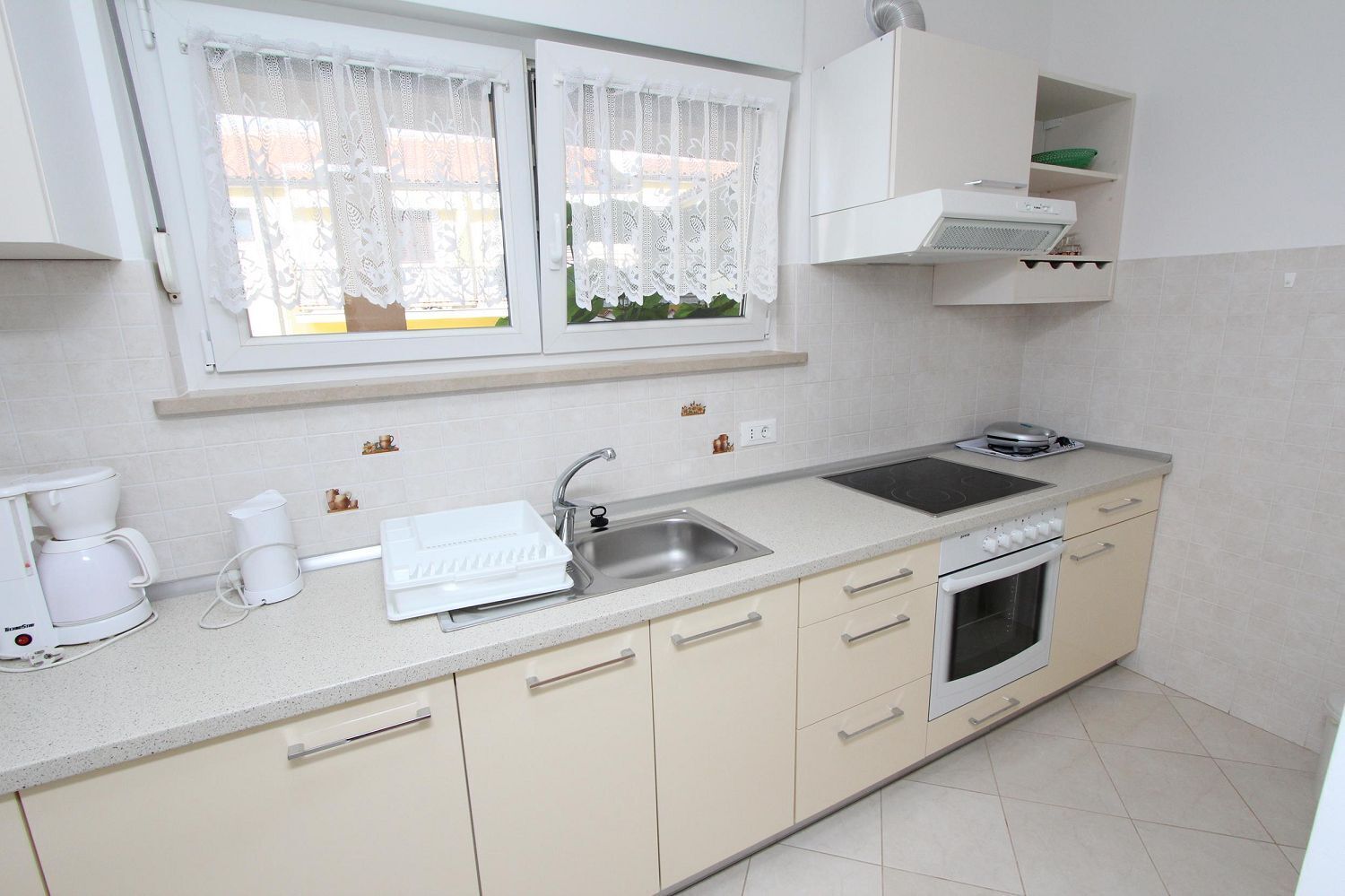 A kitchen with a sink, stove, and coffee maker.