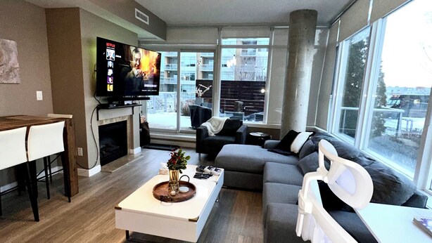 A modern living room with a sofa, coffee table, and a TV mounted on the wall. - Century park Condo Oasis (Edmonton)