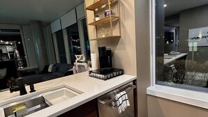 A modern kitchen with a built-in sink, a coffee machine, and a window with a view of the city. - Century park Condo Oasis (Edmonton)