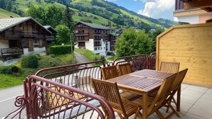 A wooden table and chairs on a balcony with a view of a mountain village. - Superb 3 room next to the chairlift in Arêches (Beaufort)