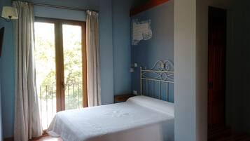 A bedroom with a bed, a window with curtains, a wall with a decorative element, and a staircase.