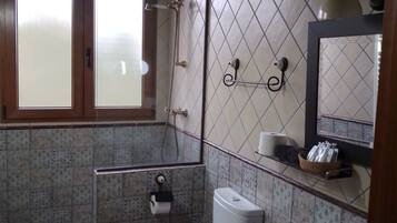 A bathroom with a toilet, bidet, sink, and a shower area.