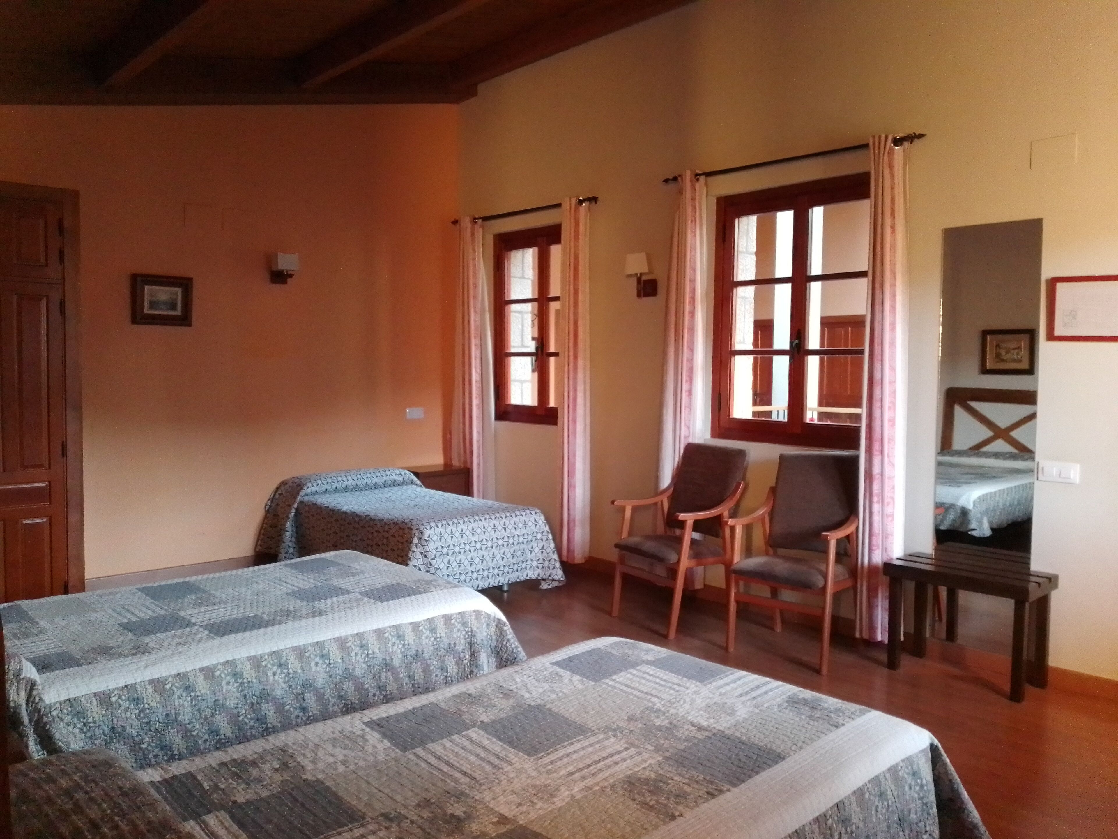 Una habitación con dos camas, una silla y una mesita.