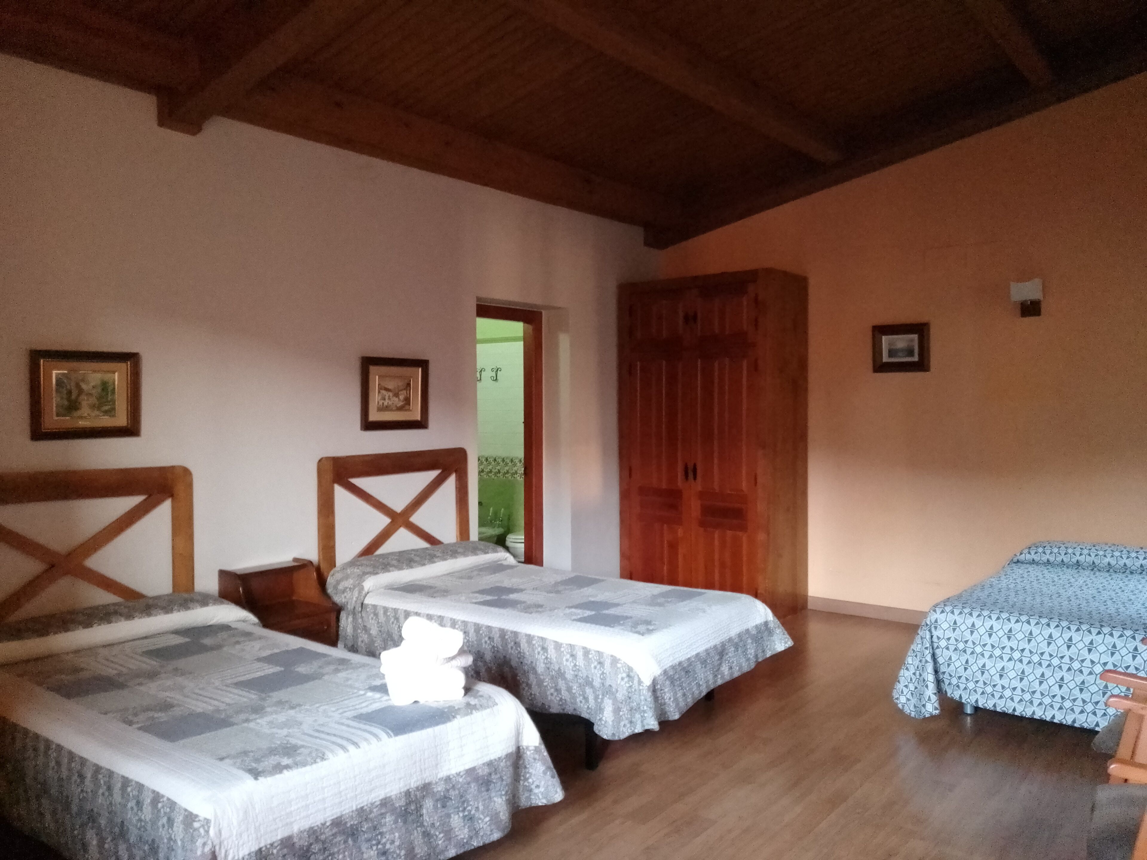 A room with two beds, wooden beams on the ceiling, and a wooden door.