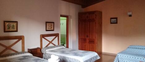A room with two beds, wooden beams on the ceiling, and a wooden door.