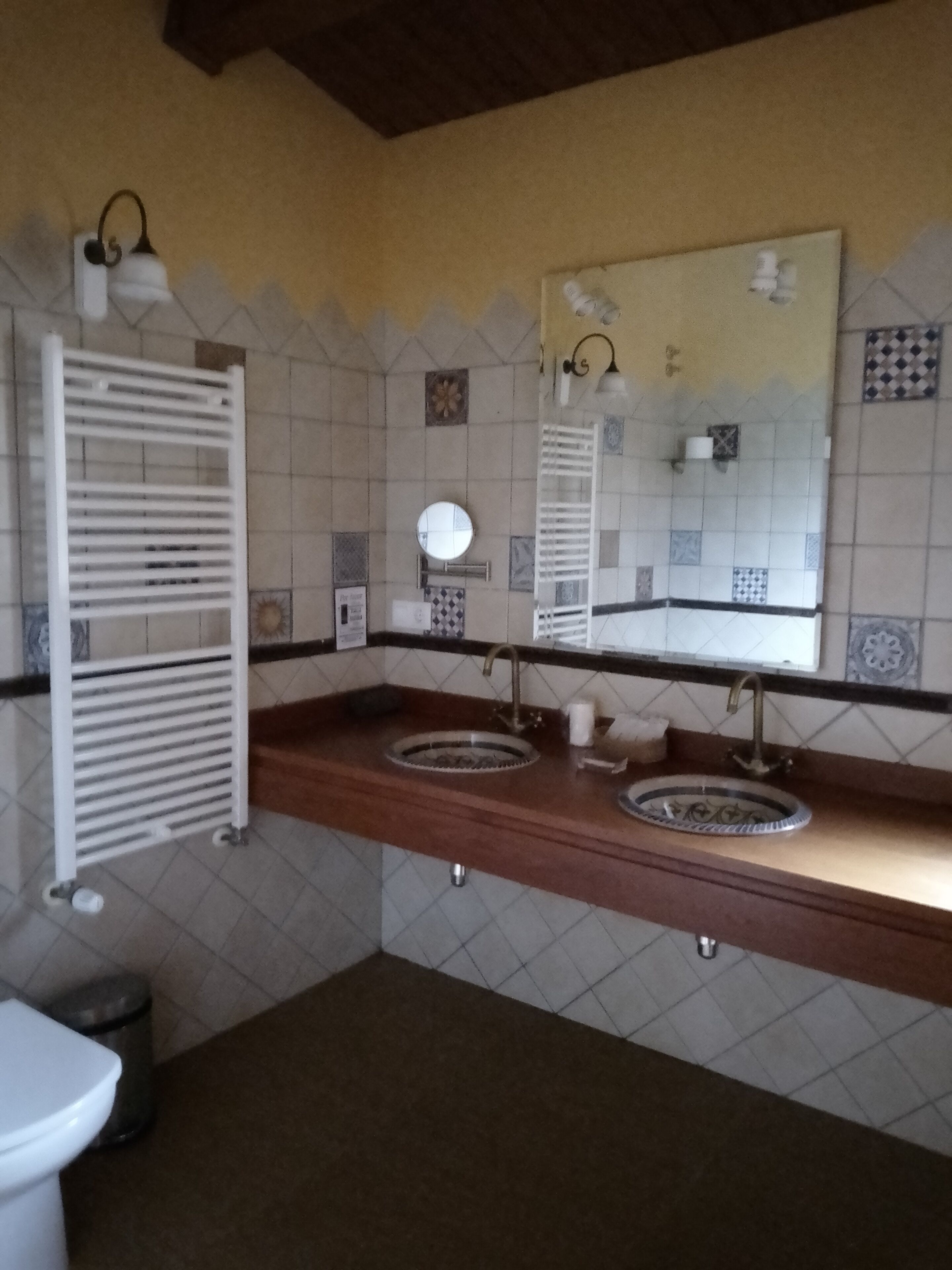 A bathroom with two sinks, a mirror, a towel rack, and a toilet.