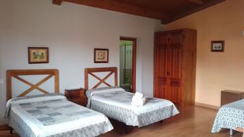 Una habitación con dos camas, vigas de madera en el techo, un armario de madera y cuadros enmarcados en las paredes.