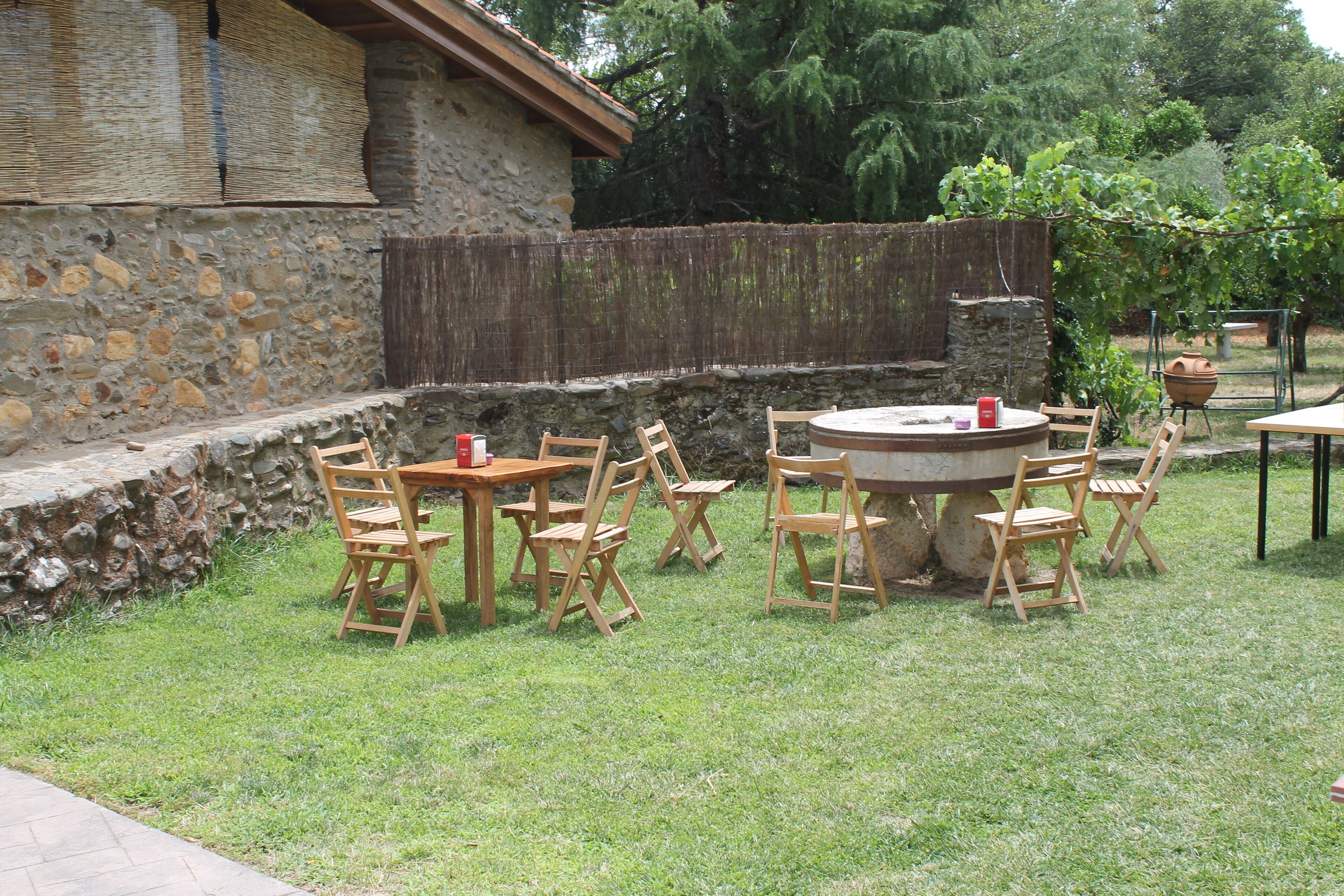 Een terras buiten met stenen muren, een ronde tafel en opklapbare stoelen.