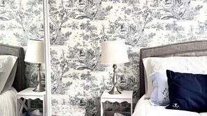 A bedroom with a bed, two bedside tables, a lamp, and a mirror.