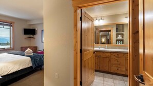 Un dormitorio con una cama, un televisor montado en la pared y un ventanal con vistas.