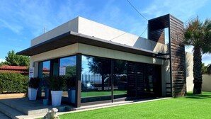A modern building with a flat roof, large glass windows, and a well-maintained lawn.