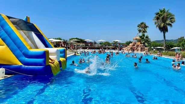A swimming pool with inflatable slides and palm trees in the background.