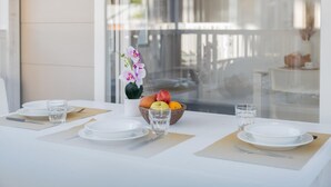 A dining table set with plates, cutlery, glasses, and a fruit bowl.