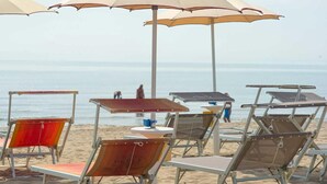 Beach chairs and umbrellas arranged on the sand, with a view of the ocean in the background.