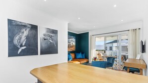 Una cocina moderna con encimera de madera, una zona de estar con sofá azul y una mesa de comedor, y obras de arte en las paredes.