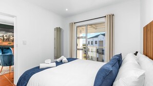 Habitación de hotel con una cama grande, vistas a edificios a través de una ventana y una silla en la esquina.