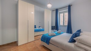 A bedroom with a bed, a TV, a wardrobe, and a window with curtains.