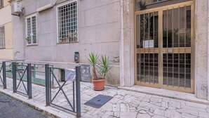 A building with a large glass door, a metal gate, and a potted plant on the sidewalk.