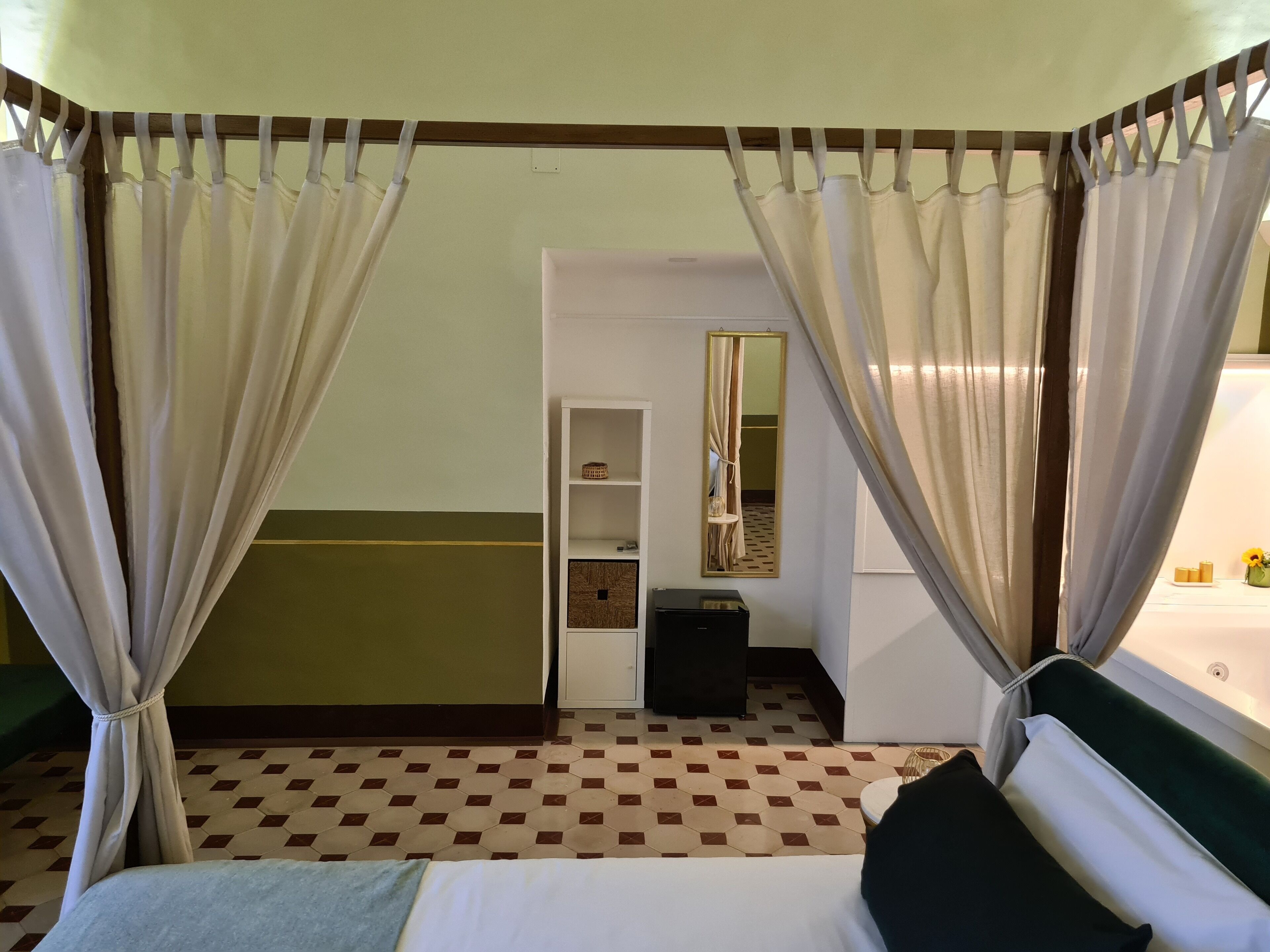 Une chambre d’hôtel avec un lit, une petite table de chevet, un miroir et une armoire.