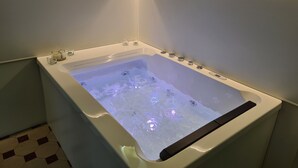 A modern bathtub with a built-in control panel, surrounded by white walls and a tiled floor. - Toscano Palace Luxury Rooms Catania (Catania)