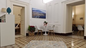 A hotel lobby with a checkered floor, a large painting of a cityscape, a white reception desk, and a seating area with chairs and a table. - Toscano Palace Luxury Rooms Catania (Catania)