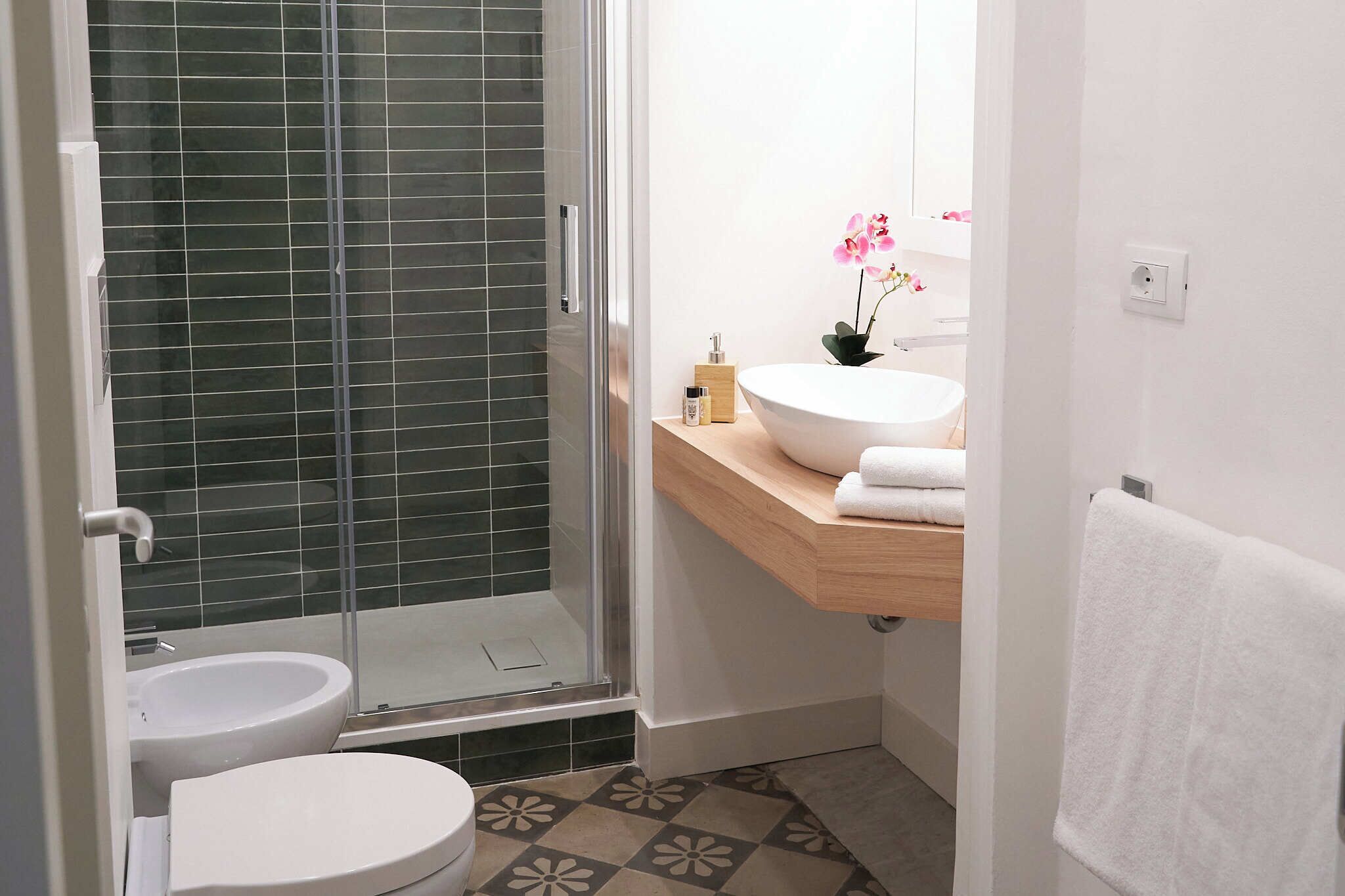 A bathroom with a glass-enclosed shower, a white sink, and a toilet.