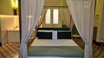 Un lit à baldaquin avec des rideaux blancs, une tête de lit verte et un couvre-lit blanc.
