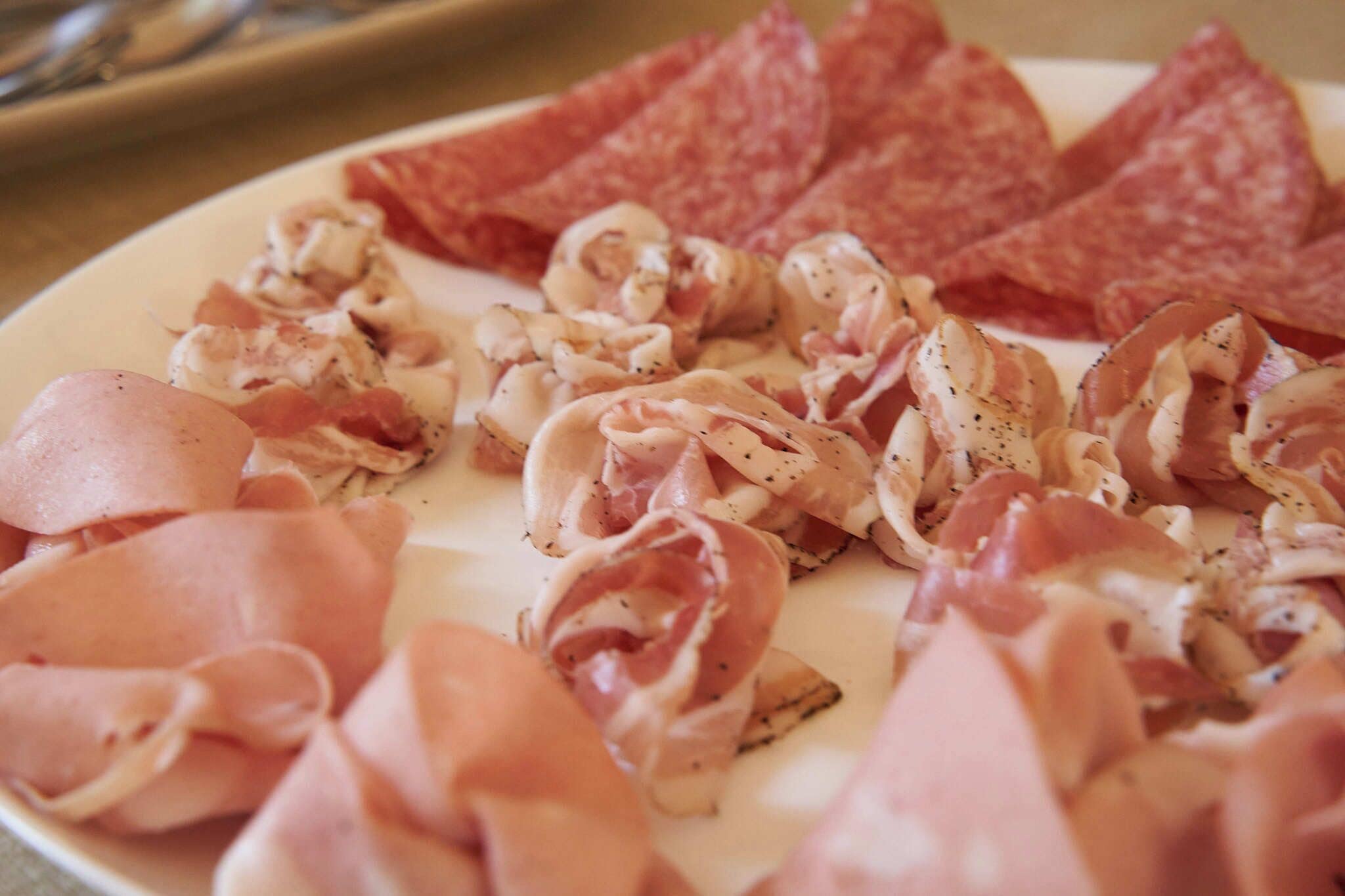 Un plato de embutidos en rodajas, como prosciutto y salami.