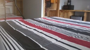 A bunk bed with a striped bedspread, a wooden desk with a coffee maker, and a TV mounted on the wall. - Charming remodeled motel room in Hemphill with Wi-Fi, mini fridge & microwave.   (Hemphill)