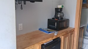 A compact kitchen with a built-in microwave, a coffee maker, and a television mounted above the counter. - Charming remodeled motel room in Hemphill with Wi-Fi, mini fridge & microwave.   (Hemphill)