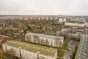 Un immeuble résidentiel de grande hauteur, composé de plusieurs étages, entouré de maisons plus petites et d’espaces verts variés.