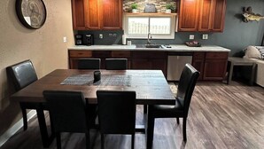 Een moderne keuken met houten kastjes, een centraal eiland en een eethoek met een tafel en stoelen.