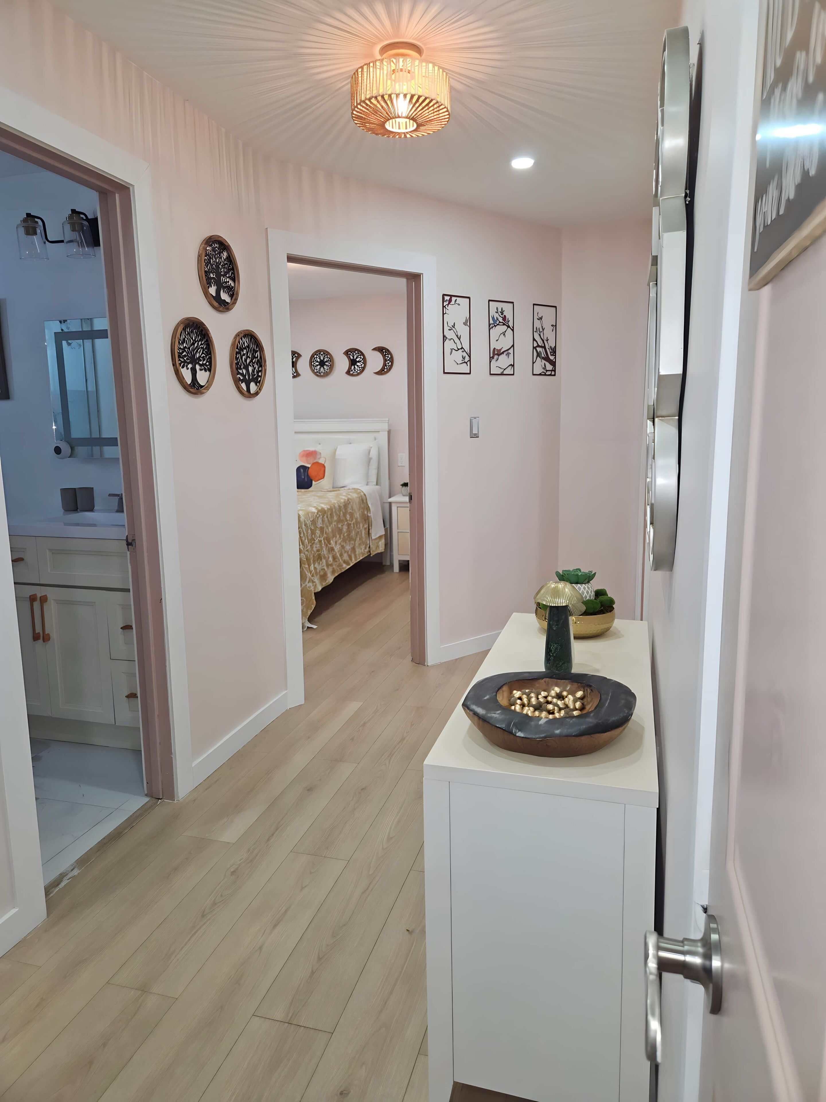 Une chambre d’hôtel moderne avec un plancher en bois, un lit recouvert d’une courtepointe à motifs, une petite table agrémentée d’objets décoratifs et des œuvres d’art mural.