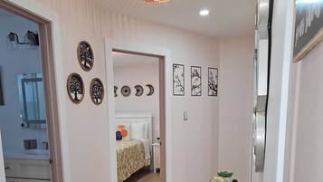 Une chambre d’hôtel moderne avec un plancher en bois, un lit recouvert d’une courtepointe à motifs, une petite table agrémentée d’objets décoratifs et des œuvres d’art mural.