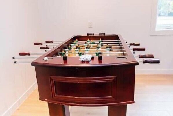 A foosball table with a wooden base and multiple rods with handles.