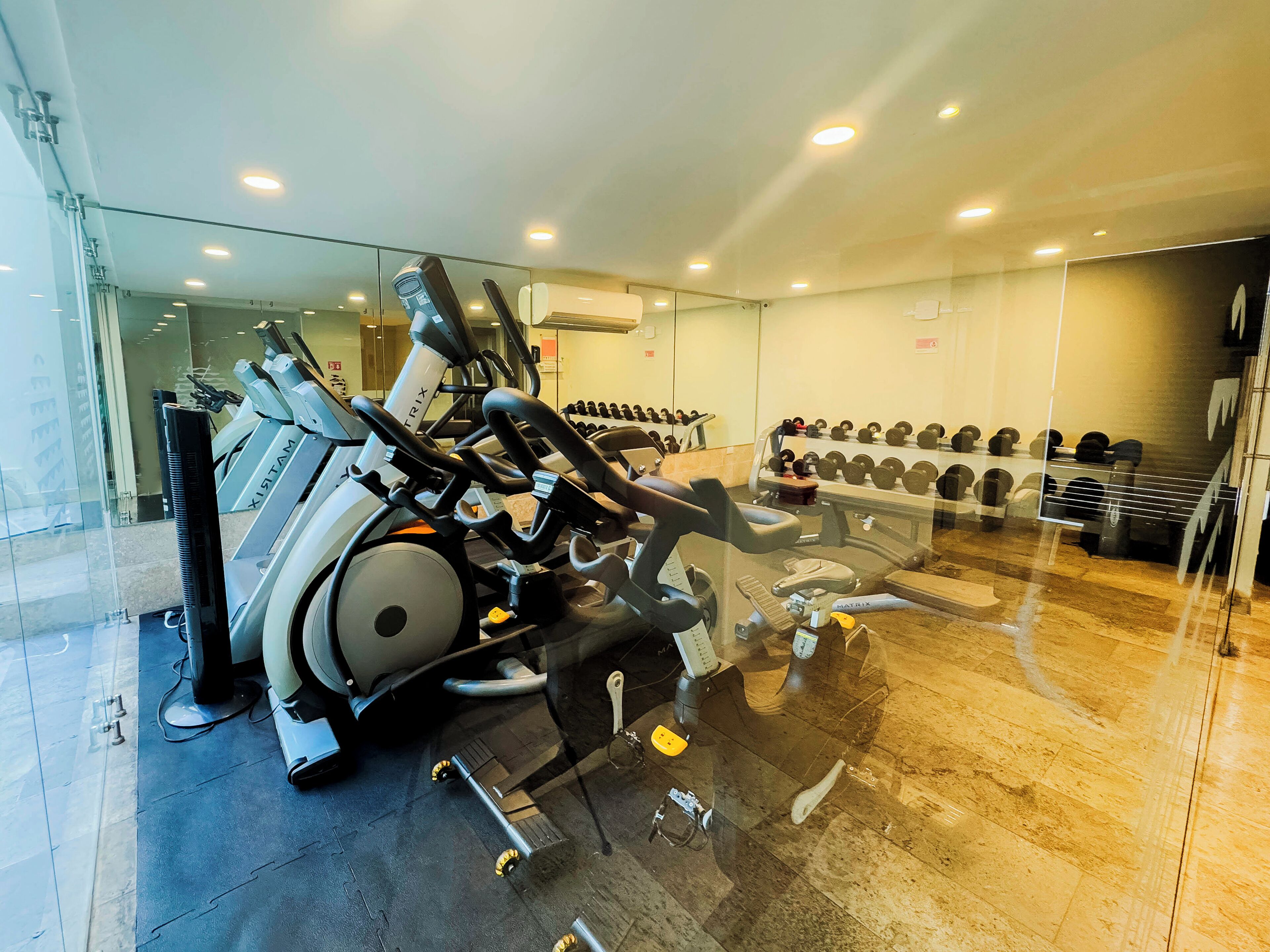 Uma academia com equipamentos de ginástica, incluindo esteiras e halteres.