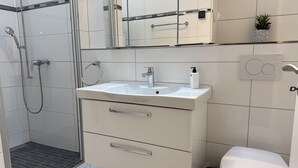 Une salle de bain moderne équipée d’une douche, d’un lavabo, de toilettes et d’un miroir.