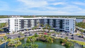 A modern hotel with a central courtyard, multiple floors, and a view of the surrounding area. - Two bedroom condo on Siesta Key with 2 pools, marina, tennis courts & more! (Siesta Key)