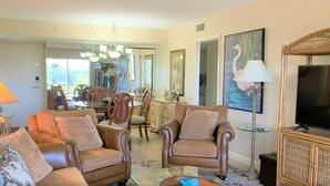 A living room with leather sofas, a glass coffee table, a television, and artwork on the walls. - Two bedroom condo on Siesta Key with 2 pools, marina, tennis courts & more! (Siesta Key)