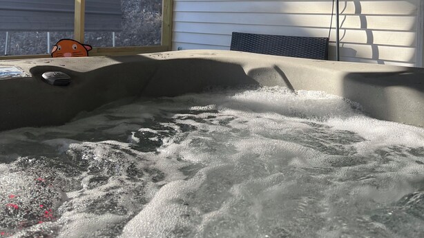 A hot tub with a television mounted on the wall, a window, and a view of trees outside. - Springside Cottage in beautiful Eminence. Great outdoor space - NEW Hot tub! (Eminence)