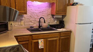 A kitchen with wooden cabinets, a stainless steel sink, a white refrigerator, and a microwave. - Springside Cottage in beautiful Eminence. Great outdoor space - NEW Hot tub! (Eminence)