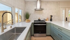 Uma cozinha moderna com uma pia de aço inoxidável, forno embutido e armários verde-claros.