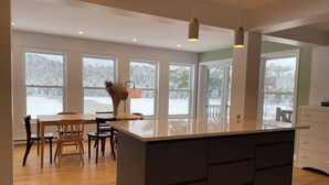 A modern kitchen with a large island, wooden dining table, and chairs.
