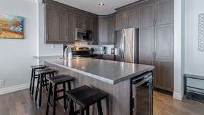 A modern kitchen with dark wood cabinets, stainless steel appliances, and a central island with bar stools.