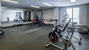 A gym with cardio machines, weightlifting equipment, and a large mirror.