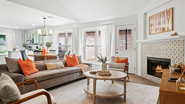 A modern living room with a sofa, chairs, a fireplace, and a dining area with a table and chairs.